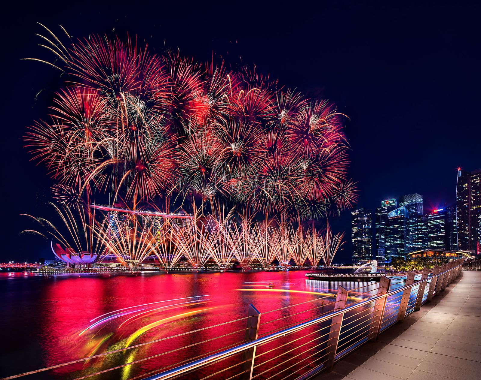 Pink fireworks photographed from a bridge with foreground leading lines