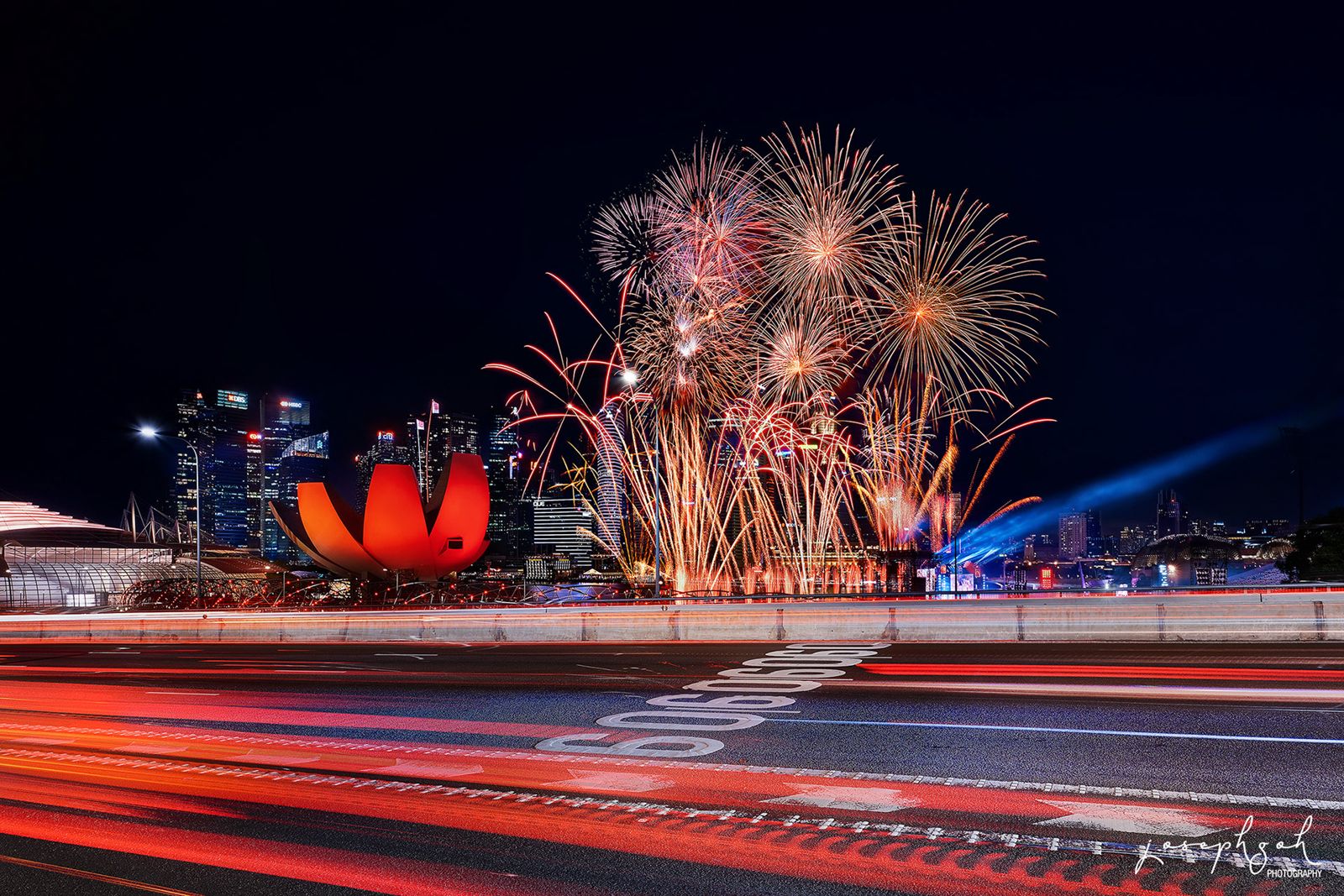 Fireworks with traffic light trails past the ArtScience Museum