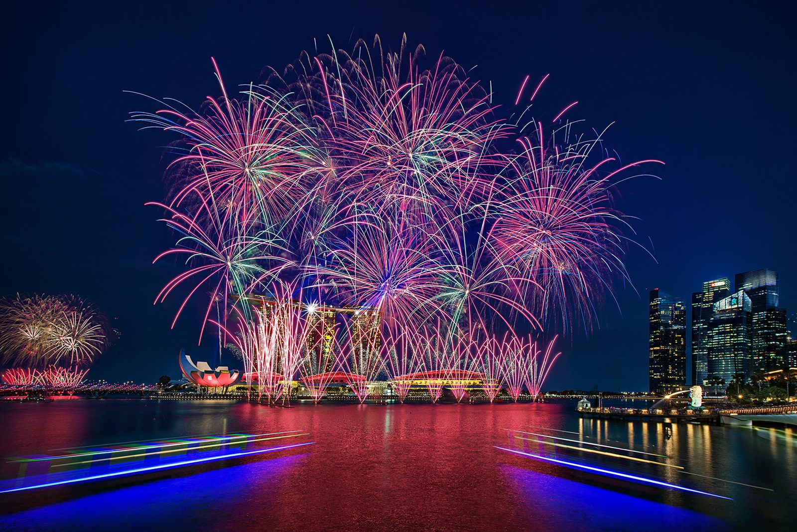 Multiple stacked colourful fireworks bursts over the bay