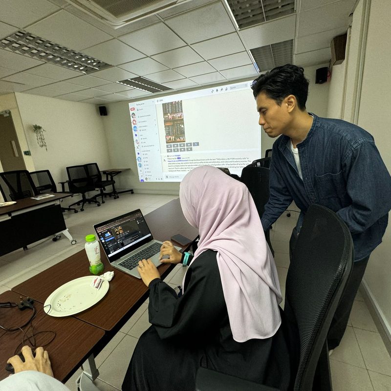 Syed working with a learner at her laptop